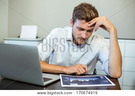 Frustrated businessman looking at book while sitting in office