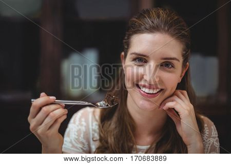 Portrait of happy woman holding desert in spoon at restaurant