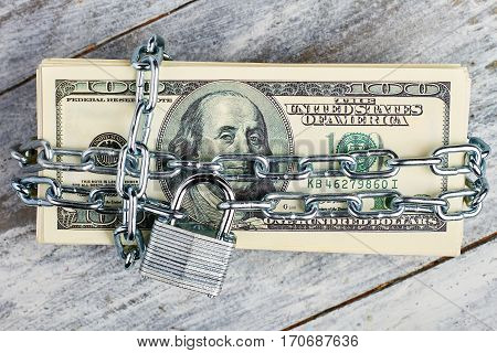 Locked dollars on wooden background. Protect your savings.