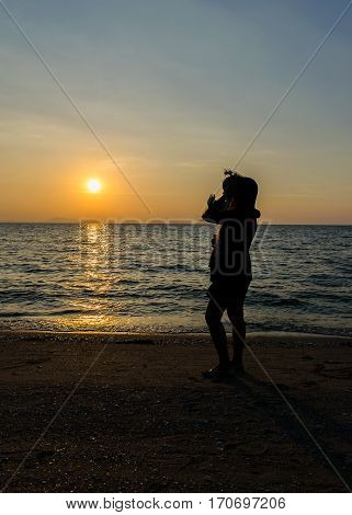 Silhouette of women and children stand watching sunset on the beach with the sea.