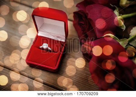 love, proposal, valentines day and holidays concept - close up of gift box with diamond engagement ring and red roses on wood (vintage effect)