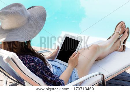 Woman using her tablet by swimming pool