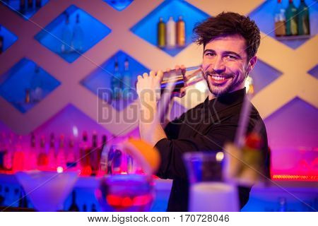 Portrait of handsome barkeeper preparing cocktail at bar counter