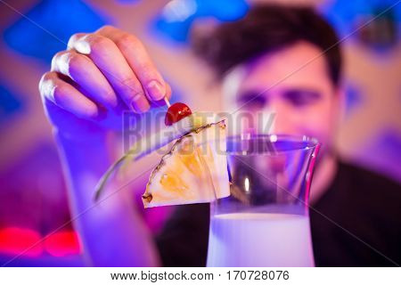 Bartender keeping fruits on cocktail glass at bar counter
