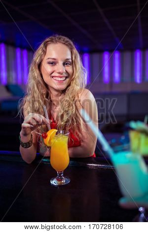 Portrait of pretty young woman with cocktail at bar counter in nightclub