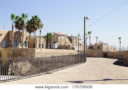 Akko (Acre) Israel. Street in the Old City of Acre - Israel. Palm trees modern street lights and ancient buildings.