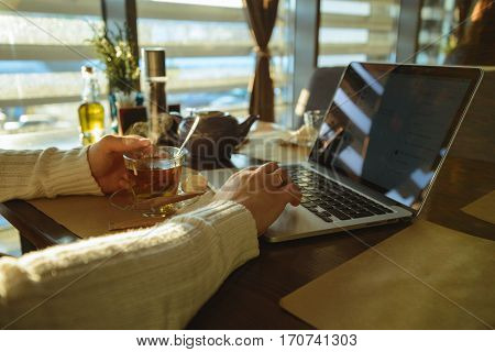 Close up of a man drinking coffee at a cafe. laptop on background