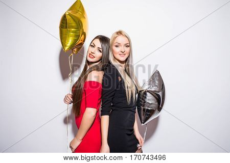 Two smiling cute young women with balloons celebrating on white