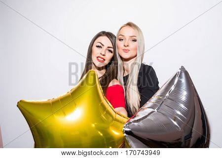 Two smiling cute young women with balloons celebrating on white