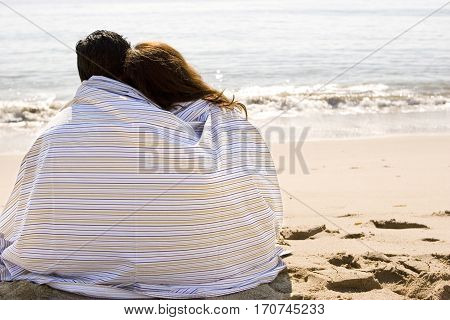 Portrait of a beautiful Hispanic couple wrapped in a blanket.