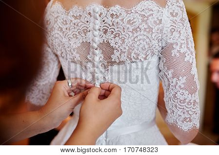 bridesmaid helping to dress the bride in a wedding morning.