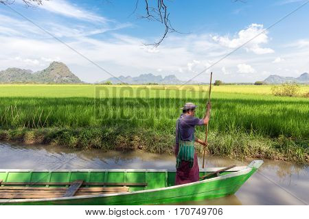 HPA-AN, MYANMAR - JANUARY 20, 2017 : A boatman, is sailing a wooden boat in the rice field river in Hpa-An, Myanmar