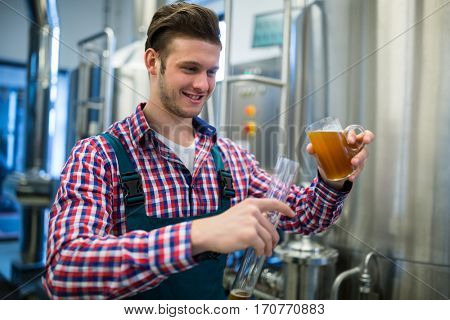 Brewer pouring beer in hydrometer cylinder at brewery factory