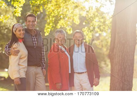 Portrait of happy family stainding by tree at park
