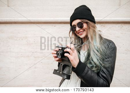 Wwoman in warm clothes and sunglasses with retro camera on the street
