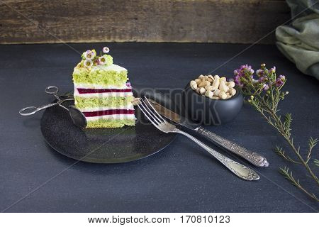 A piece of the cake with raspberry filling and pistachios on a plate