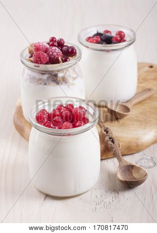 Homemade yogurt with frozen berries red currants black currants raspberries and cranberries in three banks