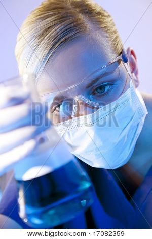 Ženské lékařské nebo vědecké výzkumník nebo lékař při pohledu na láhev červeného kapaliny v laboratoři