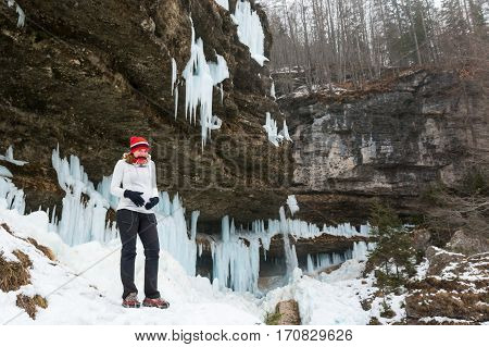 Young pregnant woman smiling on winter landscape. Icicles and snow in the background.