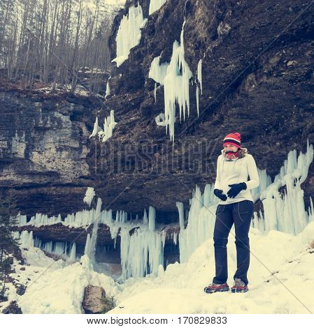 Young pregnant woman smiling on winter landscape. Icicles and snow in the background.