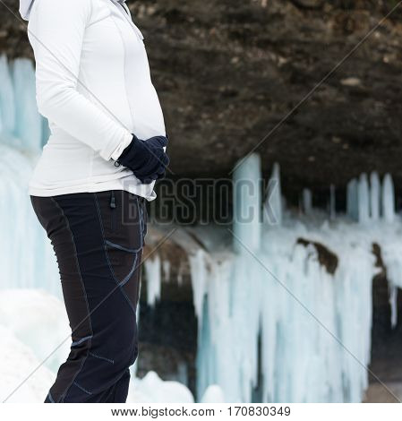 Closeup of female hands holding pregnant belly on winter background. Active pregnancy.