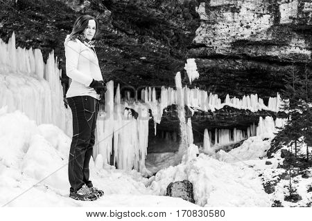Black and white portrait of pregnant woman in winter. frozen waterfall in the background.