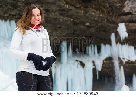 Active young pregnant woman forming a heart on her belly. Motherly love.