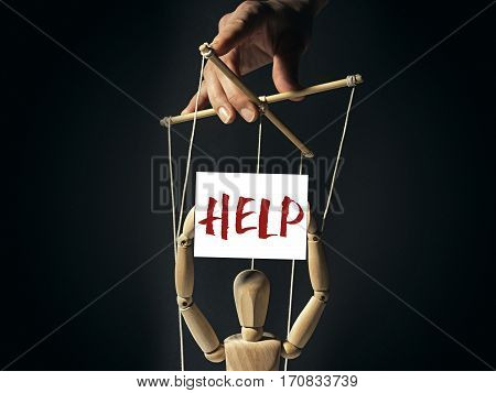 Tiran holds a puppet on strings in doll's hands a banner calling for help. Image on black background.