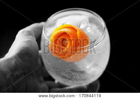 Taking with Hand a Gin Tonic with orange peel rose