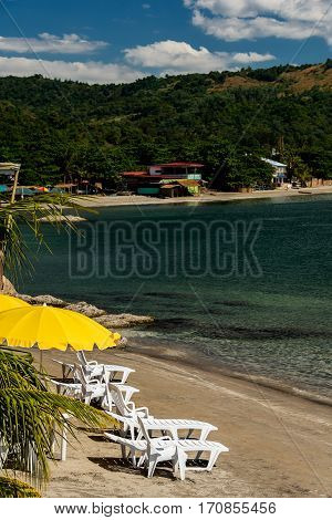 Yellow parasol and recliners on the beach in Subic bay Philippines. Vertical composition