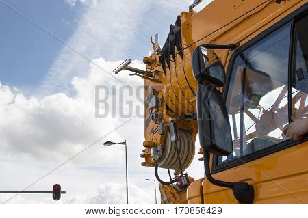 Netherlands -March, 2016 During a stop at a red traffic light crane driver stuck his arm out the window, a huge mirror machine, a red arrow on a traffic light, the clouds in the sky, clear day