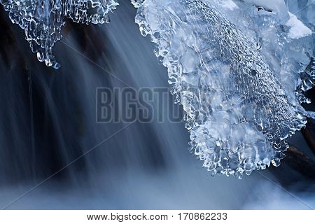 Water and ice in winter mountain stream. Cold icing shapes.