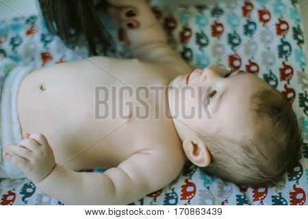 little baby lying on the bed in the diaper. thumb-sucking