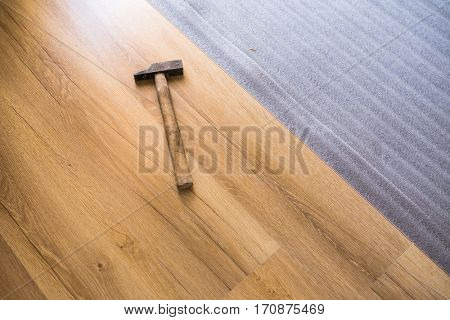 DIY, repair, building and home concept - close up of male hands lying parquet floor board/laminate flooring (shallow DOF; color toned image)