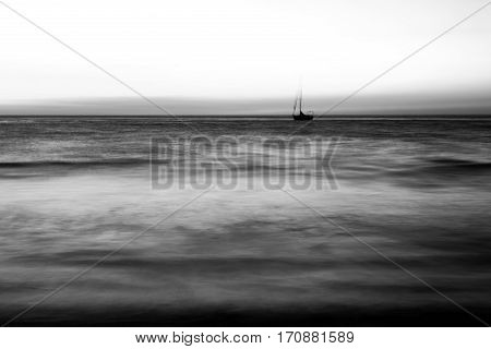Black and white image of a lone ship in the ocean.