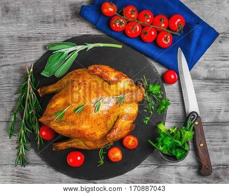Whole Roasted Chicken with Vegetables. The ingredients for chicken baked golden cherry tomatoes herbs spices thyme sage rosemary cilantro arugula knife. Light wooden background.