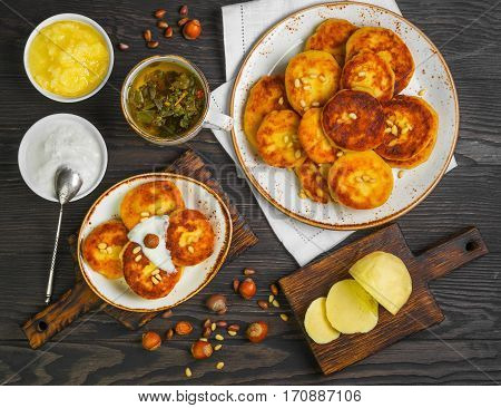 Morning breakfast Cottage cheese pancakes on white plate Herb tea. Four cottage cheese pancakes on saucer. Ingredients for Cottage cheese pancakes sour cream honey hazelnuts pine nuts butter. Top view flat lay.