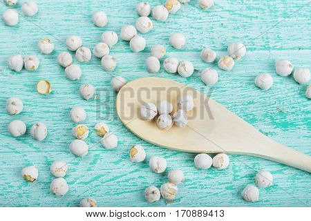 spilled chickpeas on a blue wooden background lies next to wooden spoon