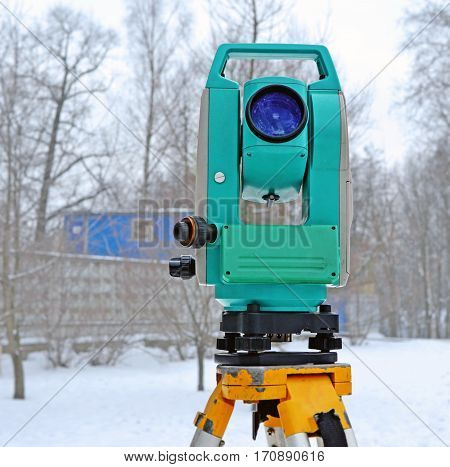 Theodolite on support near the building site in winter