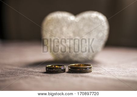 Love, Wedding And Valentine`s Day Concept. Beautiful Golden Wedding Rings And Glass Heart Selective