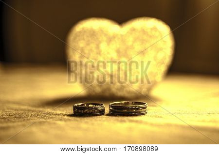 Love, Wedding And Valentine`s Day Concept. Beautiful Golden Wedding Rings And Glass Heart Selective