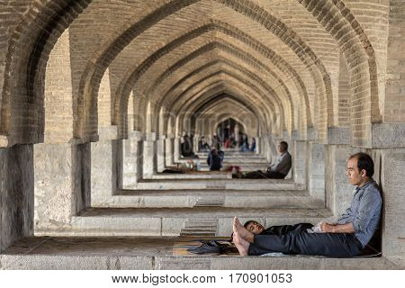 ISFAHAN IRAN - AUGUST 20 2016 : Iranian people resting under the arches of Khaju bridge in Isfahan in the warmer hours of summer