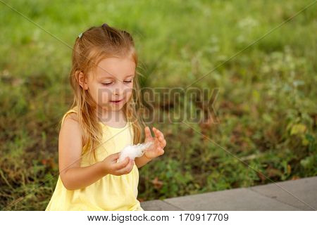 Cute little girl eating cotton candy. A walk in the summer park. Summer vacation. Outdoor Activities.