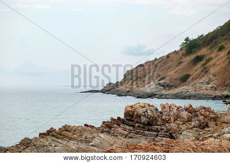 Rock cliff with view of the sea coastline at Khao Laem Ya Mu Ko Samet National Park in Thailand.