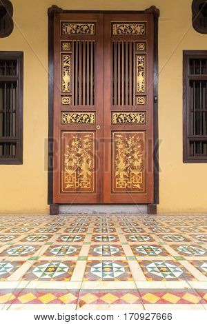 Ornate Doors of Peranakan Style exterior with Chinese wood carvings and colorful tiles entrance