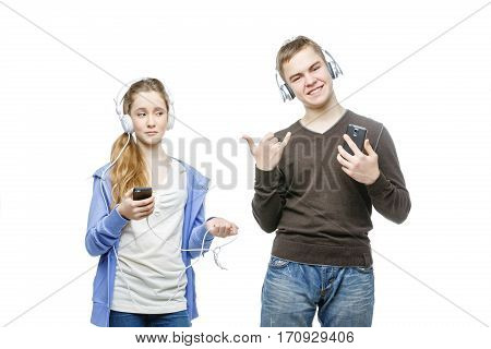 Beautiful teen age boy and girl in casual clothes standing on white background listening to music in headphones. School children. Isolated. Copy space.