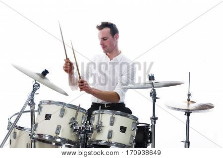 white drummer behind drum set wears white shirt and plays the drums in studio smiling