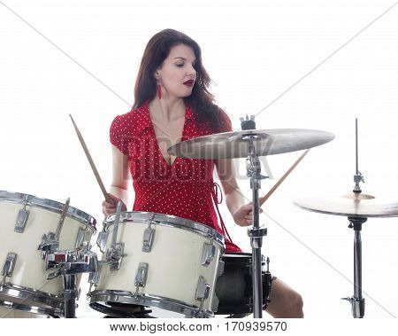 sexy brunette in red dress plays drum kit in studio against white background