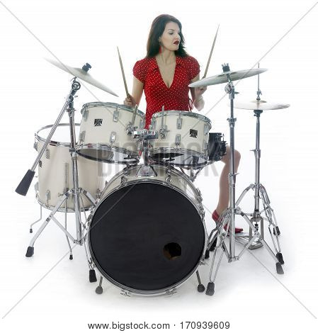 sexy brunette in red dress plays drum kit in studio against white background