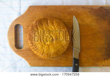 head of traditional Adygei cheese handmade with knife on wooden Board